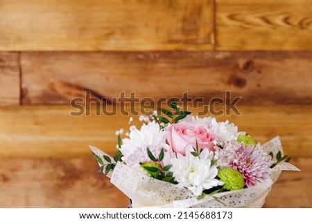 There is a beautiful bouquet of pretty and flavoring flowers. It is on the wood background. It looks presentable and great. It is ready to be sold to the customers. Royalty-Free Stock Photo #2145688173