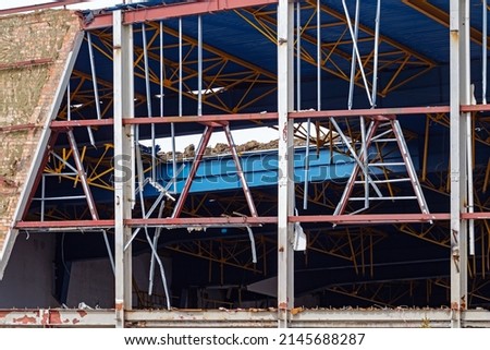 Metal rods of a broken building and ruined roof. Remains of a destroyed industrial building. Demolition Building. Royalty-Free Stock Photo #2145688287
