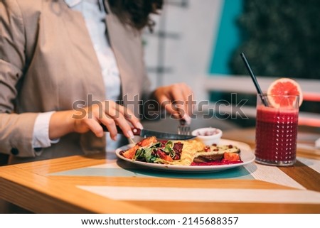 A middle-aged businesswoman enjoys a healthy meal and fresh beetroot and grapefruit juice at the organic food restaurant. Royalty-Free Stock Photo #2145688357