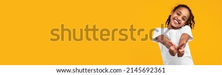 Joyful black girl gesturing thumbs up at camera and smiling, happy cheerful african american female child showing sign of approval over yellow studio background, wide horizontal banner, copy space Royalty-Free Stock Photo #2145692361