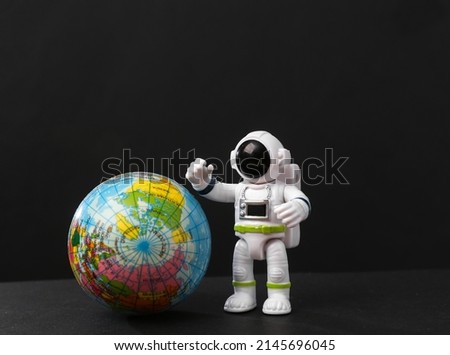 Toy astronaut with globe on a black background