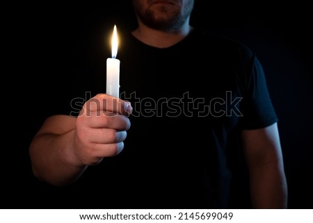 Candle in hand burns in the dark.