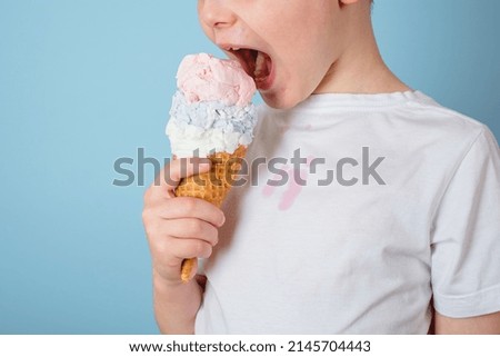 Unrecognizable child eating ice cream. dirty stain of strawberry ice cream on white clothes. daily life stain and cleaning concept . High quality photo Royalty-Free Stock Photo #2145704443