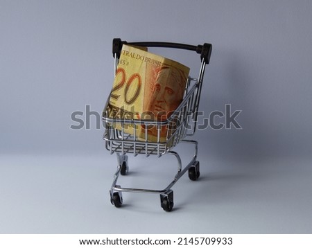 brazilian banknote of twenty reais in a shopping cart on white background Royalty-Free Stock Photo #2145709933