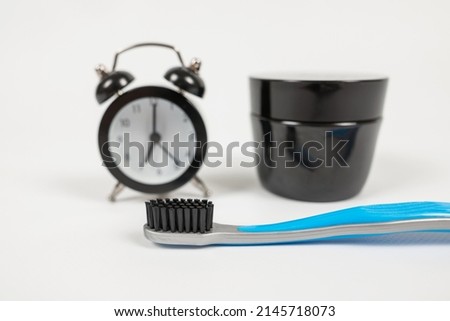 Close up of toothbrush alarm clock and tooth powder on white