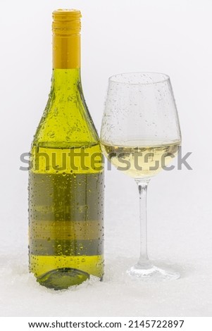 a glass of wine and a bottle on the cold snow 
