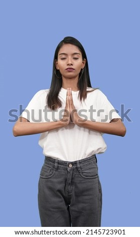 Indian girl or woman holding hands in namaste or prayer, keeping eyes closed while practicing yoga and meditation. spiritual concept
