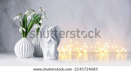 Praying angel and snowdrops flowers on table, abstract background. Religious church holiday. symbol of faith in God, Christianity. Easter, Feast of Annunciation to the Blessed Virgin Mary. banner