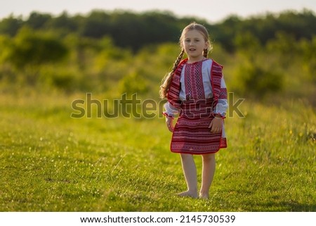 girl in a Ukrainian dress walks along the lawn in nature