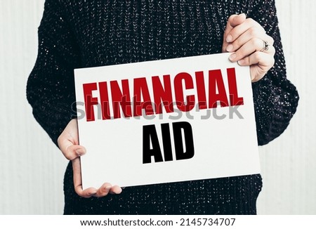 A person in black sweater showing white card with text Financial Aid.