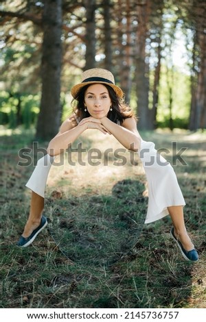 Beautiful girl in small straw hat and in white suit with big mirror in the big public park. Soft focus and blur. Travel concept.