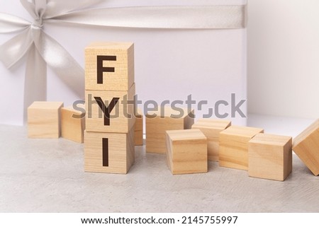 fyi - letters on wooden cubes. concept on light gift box background. business as usual concept image. space for text in right. front view. fyi - short for For Your Informtion