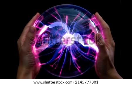 Hands holding plasma light ball on black background Royalty-Free Stock Photo #2145777381