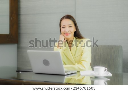 Portrait beautiful young asian woman use computer laptop with smart mobile phone on working table at interior room
