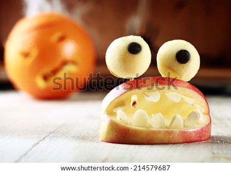 Cute homemade Halloween apple decoration of an open mouth with teeth topped with googly dough eyes on toothpicks for a scary but healthy favor to give children trick-or-treating