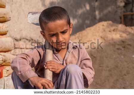 child boy sitting holding a shovel on a construction site