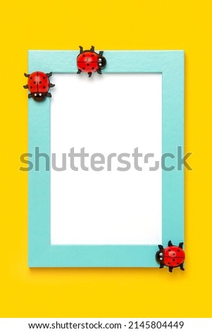Blue frame with white card and ladybugs on yellow background. Mockup, Top view, Flat lay. Layout, template for your design.