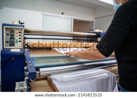 A worker printing on t shirt in workshop. clothing industry concept. Heat transfer machine.