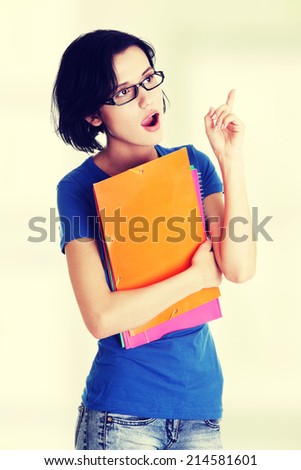 Student woman with coloured note pad pointing up. Surprised.