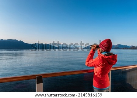 Vacation adventure. Alaska Glacier Bay cruise ship passenger looking at Alaskan mountains with binoculars exploring Glacier Bay National Park, USA. Woman on travel Inside Passage enjoying view Royalty-Free Stock Photo #2145816159