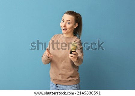 Young woman with professional microphone on blue background