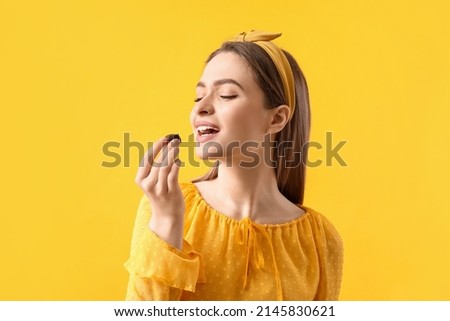 Beautiful young woman with delicious chocolate candy on color background Royalty-Free Stock Photo #2145830621