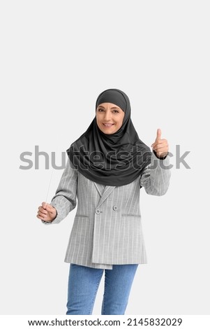 Muslim music teacher showing thumb-up on light background