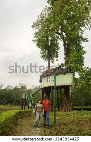 A couple taking photo in front of a wooden tree house cottage at dhupjhora elephant camp at Garumara Forest.