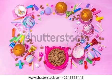 Pet cat happy birthday background with set different cats and kitty snack, food and toys, cat muzzle shape bowl, birthday cupcakes with happy birthday candles, accessories. Flatlay on pink background