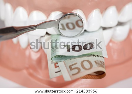 Dentures biting euro banknotes close up