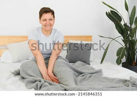 Happy fresh beautiful mature older woman awake after healthy sleep stretch wake up in cozy comfortable bed, smiling middle aged lady enjoy good morning looking at camera, close up portrait, top view