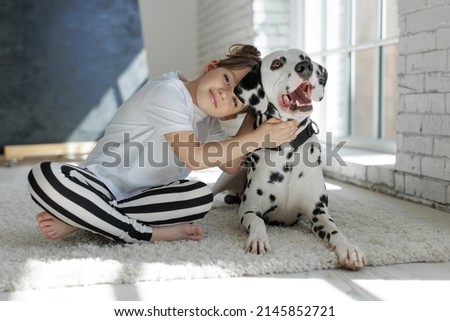 Child with a dog. A happy girl lies on a carpet with a Dalmatian dog. High quality photo