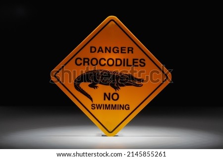 Warning sign Danger Crocodiles in the dramatic light. Danger crocodiles, no swimming.