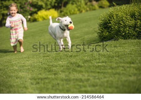 Young girl with dog playing in garden Royalty-Free Stock Photo #214586464