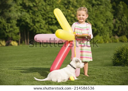 Young girl with dog and balloons in garden