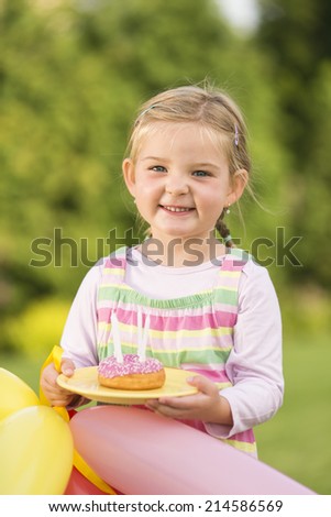Young girl with birthday doughnut in garden