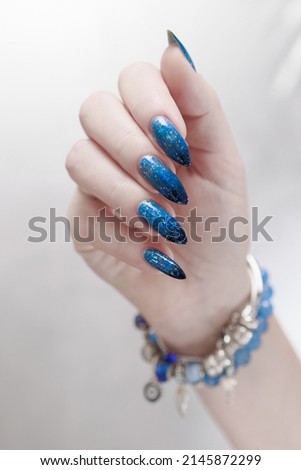 Female hand with long nails and blue-black thermo french nail polish
