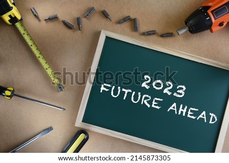 2023 future ahead on chalkboard with tools supplies on brown background. Business challenge concept and effort idea