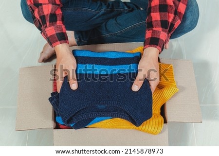 man holding a crate of second-hand clothes unused clothes