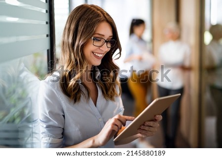 Attractive young businesswoman using a digital tablet while standing in front of windows in office Royalty-Free Stock Photo #2145880189