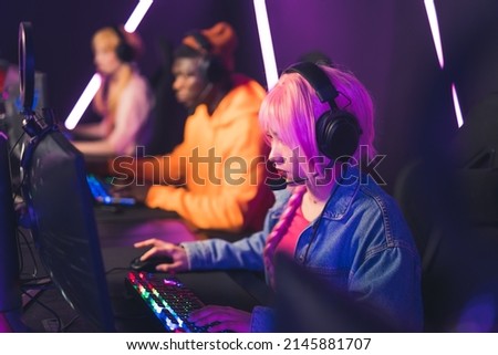 young pink-haired girl participating in video games tournament cyber sport concept medium closeup neon lights indoors. High quality photo