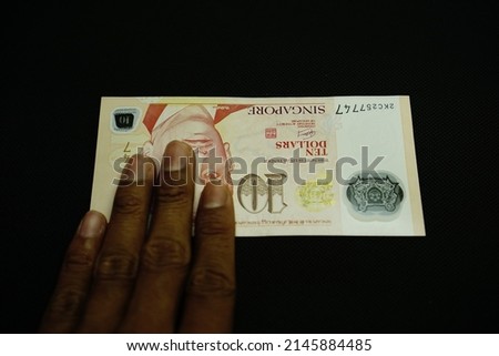 10 SGD, Ten Singapore Dollar money was held by businessman, isolated on black background 