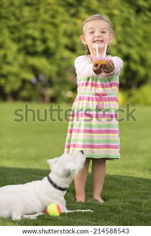 Young girl with birthday doughnut and dog in garden