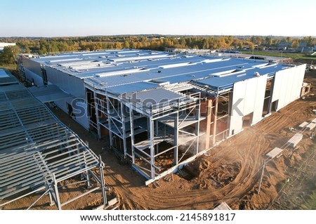 Warehouse Construction from metal structure. Industrial building on light gauge steel framing. Frame of modern hangar or factory. Construction site with steel structure warehouse. Top view on a roof. Royalty-Free Stock Photo #2145891817