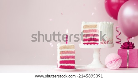 Pink ombre birthday cake with balloons and slice of birthday cake and candle