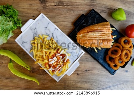 Top view of table scene with assorted take out or delivery foods. Meat and chicken doner kebab sandwich, wrap and on the plate with vegetables and sauce, including fries and pickles.