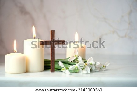Wooden cross, snowdrops flowers and candles on table, blurred abstract background. Religious church holiday. symbol of faith in God, Christianity Feast, Easter, Palm Sunday, Lent Royalty-Free Stock Photo #2145900369