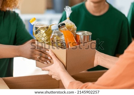 charity, donation and volunteering concept - close up of volunteers giving box of food at distribution or refugee assistance center Royalty-Free Stock Photo #2145902257