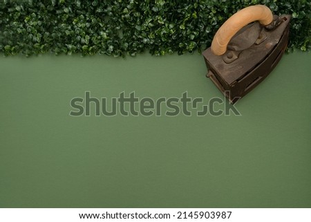 Abstract concept of flattening the hedge with the steam iron. Minimalistic scene on a green background