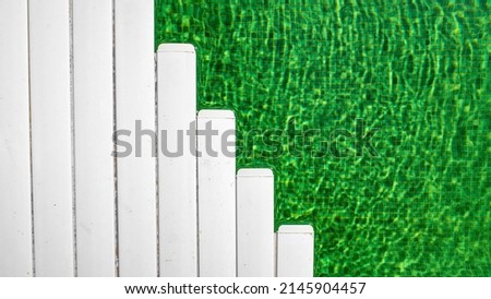 Green swimming pool half covered with white plastic tiles. 